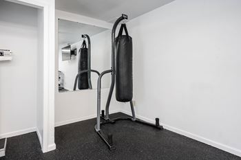 A black punching bag is hanging from a stand in a room.
